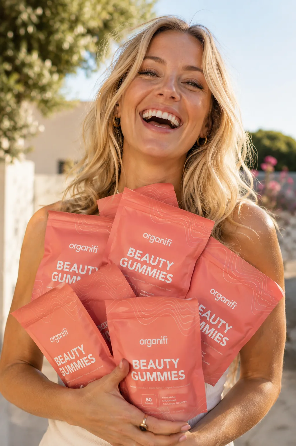 Smiling woman holding Organifi Beauty Gummies pouches